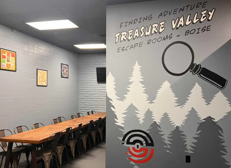 The event room’s painted wall: Finding Adventure, Treasure Valley Escape Rooms, Boise, with pines and a magnifying glass